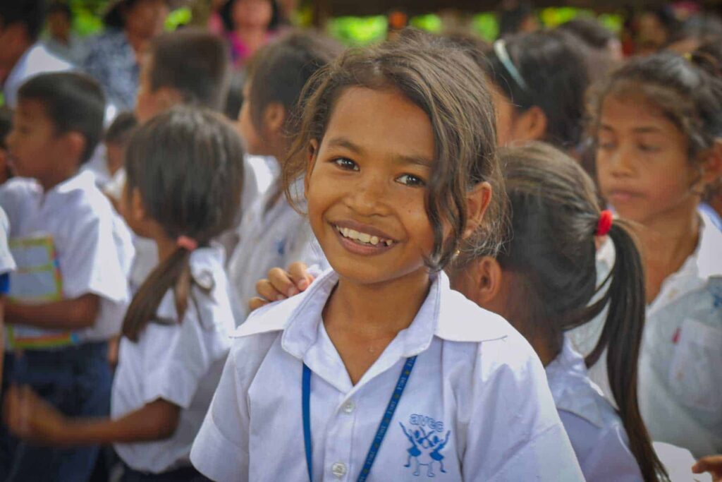 Jeune fille cambodgienne étudiante en uniforme scolaire de l'ONG AVEC, souriante en classe.